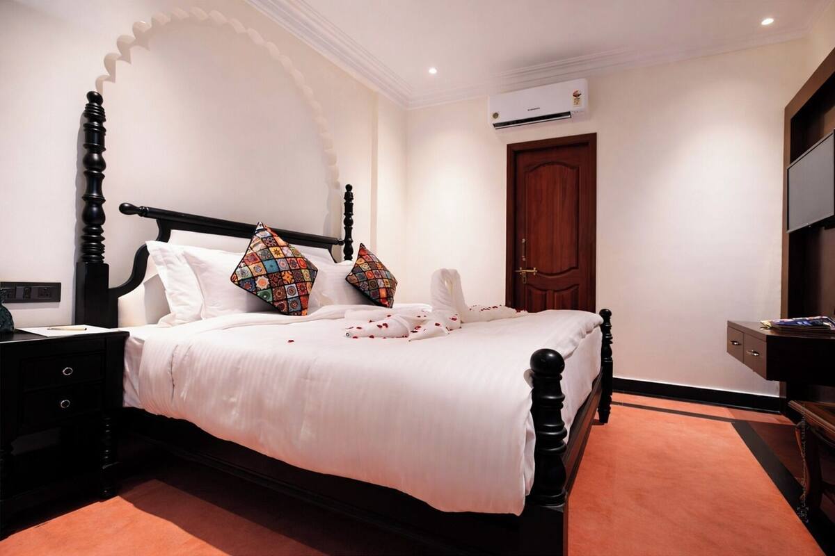 A neatly made bed with a black headboard, white bedding, and colorful pillows.