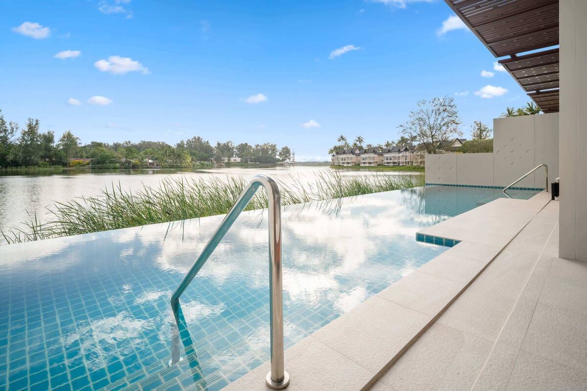 An infinity pool with a clear view of a lake and distant buildings.