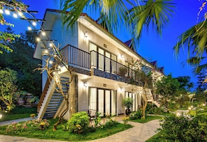 A two-story hotel with a balcony, a staircase, and a well-lit entrance.