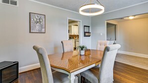 Un comedor con una mesa de madera, cuatro sillas y una lámpara colgante.