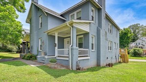 Une maison à deux étages avec un porche, une cheminée et une pelouse bien entretenue.