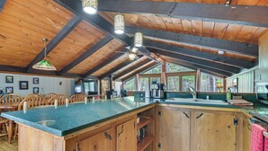 Een keuken met houten kastjes, een groot eiland en hangende pendantlampen.