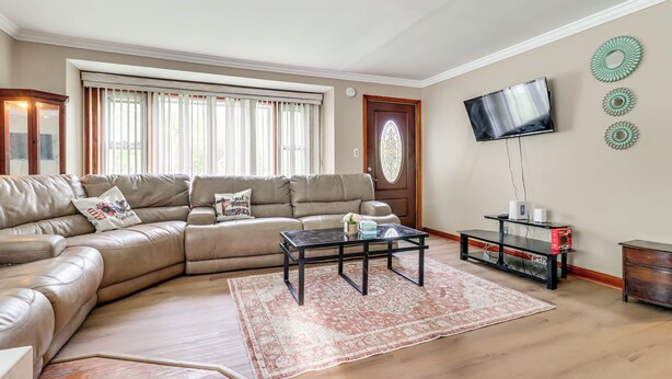 Un salon comprenant un canapé d’angle, une table basse, un téléviseur fixé au mur et un miroir décoratif.