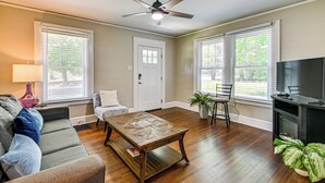 A living room with a sofa, coffee table, TV stand, and potted plant. - Charlotte Duplex Close to Uptown and Sports (Charlotte)
