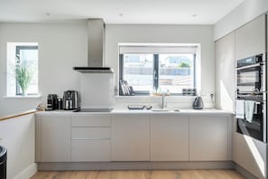 Eine moderne Küche mit Fenster, Backofen und Kaffeemaschine.