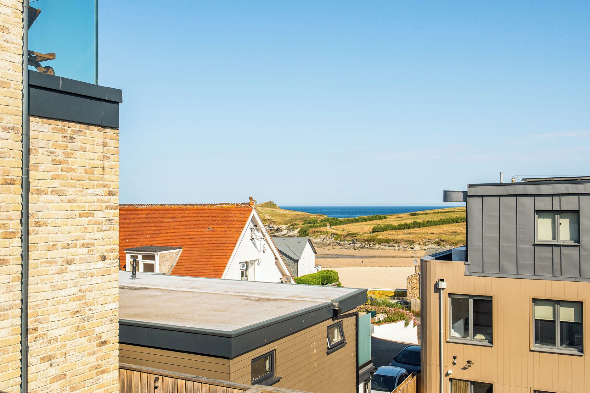 A coastal residential area with modern buildings, a clear sky, and a view of the sea.
