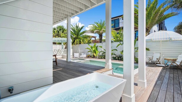 Un espace bien-être comprenant un jacuzzi, une terrasse en bois et des sièges extérieurs.