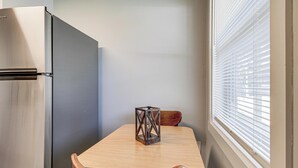 A compact kitchen with a refrigerator, a wooden dining table, and a window with blinds. - 3 Mi to Dtwn: Pet-Friendly Studio in Huntsville (Huntsville)