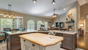 A spacious kitchen with a large island, a dining area with a couch, and a fireplace. - Hot Tub, Game Room! Ozarks Family Retreat By Lake (Eldon)