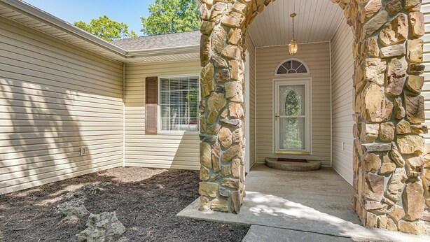 A house with a stone archway leading to a front door, a window with blinds, and a clear sky. - Hot Tub, Game Room! Ozarks Family Retreat By Lake (Eldon)