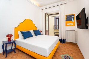 Ein Schlafzimmer mit Bett, Nachttisch, Fernseher und einem Fenster mit Vorhängen.