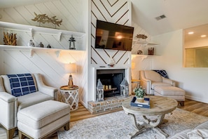 A living room with a fireplace, a television, and a sofa. - Lake Conroe Waterfront in Walden! Lovely 4 Bdrm! (Montgomery)