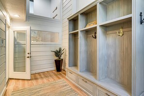 A hallway with a wooden bench, a potted plant, and a door with frosted glass panels. - Lake Conroe Waterfront in Walden! Lovely 4 Bdrm! (Montgomery)