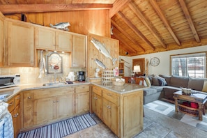 Eine geräumige Küche mit Holzausstattung, einer großen Kochinsel und einem Essbereich mit Sofa und Couchtisch.
