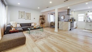 Un vaste espace de vie comprenant un canapé, un pouf, une table basse et des œuvres d’art accrochées aux murs.