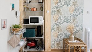 Uma cozinha equipada com micro-ondas, chaleira e prateleiras com utensílios.