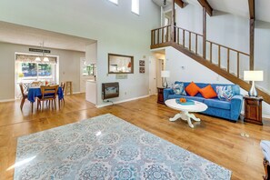 A spacious living room with a wooden staircase, a dining area with a table and chairs, and a blue sofa with orange cushions. - Dockside Sunset Retreat! Lake Sinclair Near US-441 (Milledgeville)