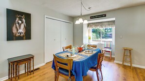 Ein Essbereich mit einem Tisch für vier Personen, einem Holzstuhl, einem kleinen Beistelltisch und einem Bild an der Wand.
