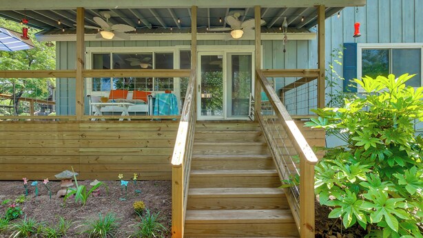 Eine Holzterrasse mit einer Treppe zu einem überdachten Bereich, ausgestattet mit Deckenventilator und Beleuchtung.