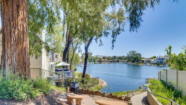 A lakeside patio with stone benches and a pathway leading to a house.
