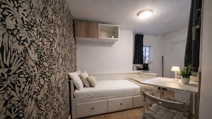 A bedroom with a bed, a desk, a chair, a mirror, a shelf, and a window. - Comfortable and cozy studio – 2 people – La Doutre district, Angers (Angers)