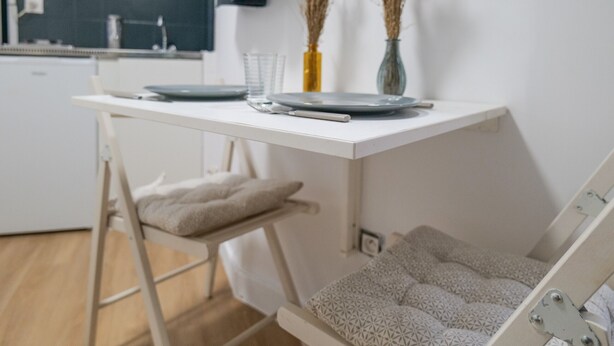 A compact kitchen with a white countertop, a small dining table, and a foldable chair. - Comfortable and cozy studio – 2 people – La Doutre district, Angers (Angers)
