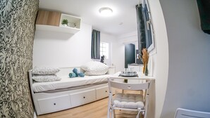 A bedroom with a bed, bedside table, chair, and a small desk with a mirror. - Comfortable and cozy studio – 2 people – La Doutre district, Angers (Angers)