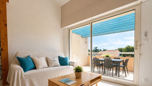 Uma sala de estar moderna com sofá, mesa de centro e porta de vidro deslizante para um pátio externo.