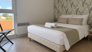 Quarto com cama, janela, cadeira e parede com padrão de folha.