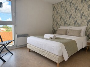 Ein Schlafzimmer mit einem Bett, einem Fenster, einem Stuhl und einer Wand mit einem Blattmuster.
