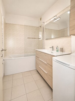 Ein Badezimmer mit einer Badewanne, einem Waschbecken, einem Spiegel und einer Toilette.