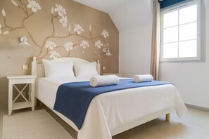 Ein Schlafzimmer mit Bett, Nachttisch in Weiß und Wandgemälde.
