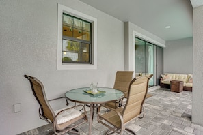 A patio with a round glass table, wicker chairs, a cushioned sofa, and a window with curtains. - Punta Gorda Home: Great for Nurses & Professionals (Punta Gorda)