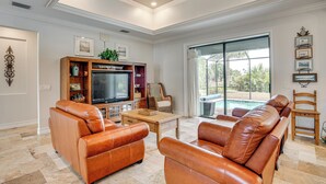 A living room with leather sofas, a flat-screen TV, a coffee table, and a large sliding glass door leading to an outdoor area. - Punta Gorda Home: Great for Nurses & Professionals (Punta Gorda)