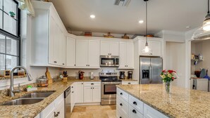 A modern kitchen with white cabinets, granite countertops, stainless steel appliances, and a hanging pendant light. - Punta Gorda Home: Great for Nurses & Professionals (Punta Gorda)