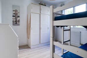 Une chambre avec un lit superposé, une armoire blanche et un panneau fixé au mur.