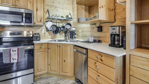 Een keuken met houten kastjes, een RVS magnetron, een oven, een vaatwasser en een koffiezetapparaat.