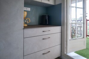 Eine Küche mit Kaffeemaschine, einer gelben Tasse und einem Schrank mit Schubladen.