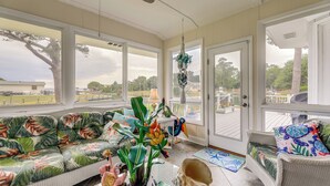 A sunroom with wicker furniture, a large window, and a view of the outdoors. - On the ICW: Personal Dock, Ocean Fishing & Beach! (Newport)