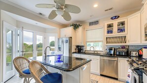 A kitchen with a central island, white cabinets, stainless steel appliances, and a ceiling fan. - On the ICW: Personal Dock, Ocean Fishing & Beach! (Newport)