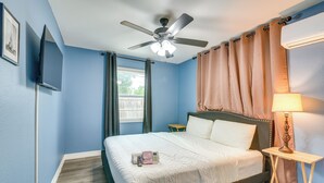 A hotel room with a bed, a ceiling fan, a window with curtains, a bedside table with a lamp, and a wall-mounted TV. - 6 Mi to TMC & Hermann Park! SE Houston Home (Houston)