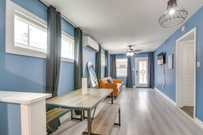 Ein Zimmer mit Esstisch, Sofa, Deckenventilator und einem Fenster mit Vorhängen.