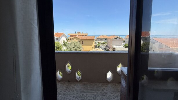 Ein Balkon mit Blick auf Wohnhäuser und einen klaren Himmel.