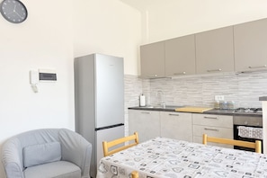 Una cocina compacta con refrigerador, un lavamanos y una mesa de comedor con sillas.