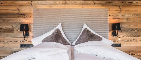A bed with a quilted headboard, two bedside lamps, and a wooden wall.