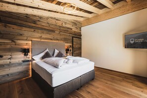A modern bedroom with a wooden ceiling, a bed with white linens, and a mounted artwork on the wall.