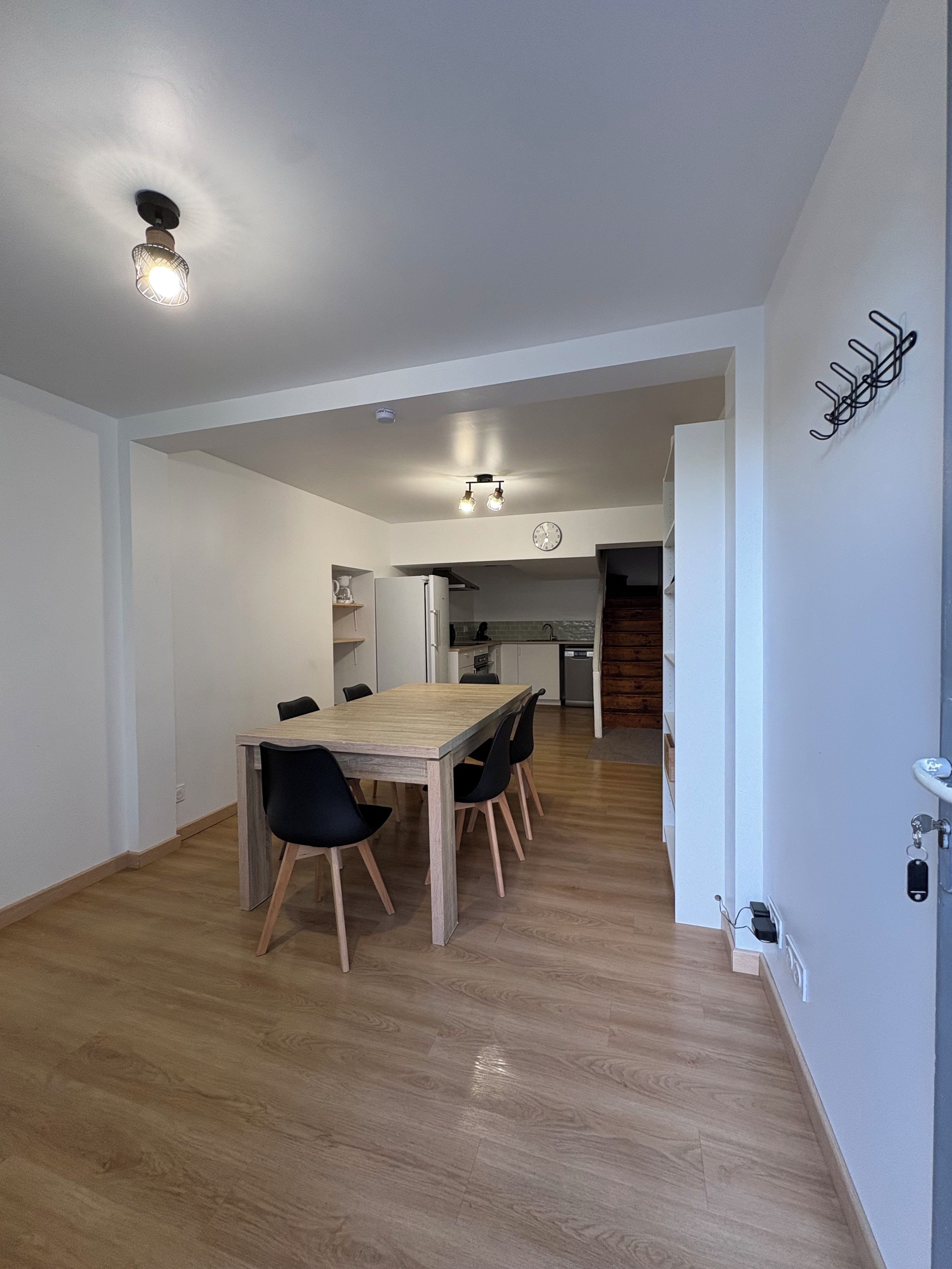 Eine moderne Küche mit Einbauofen, ein Essbereich mit Holztisch und Stühlen sowie eine Treppe zu einer weiteren Ebene.