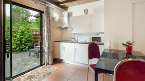 A kitchen with white cabinets, a microwave, and a dining area with a table and chairs. - Sunset Village A Apartment with Sea View, Wi-Fi and Air Conditioning (Sao Jorge)