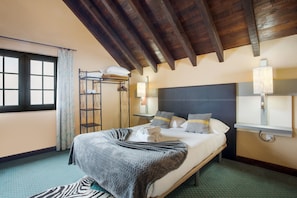 Ein Hotelzimmer mit Bett, Fenster, einer Leiter und einer Lampe.