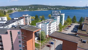 A residential area with modern apartment buildings, a parking lot, and a lake in the background. - Comfy 1BR Apt with Sauna - Best Location (Jyväskylä)